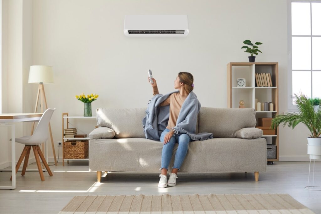 Woman enjoying cool fresh air in her living room with air conditioner on the wall